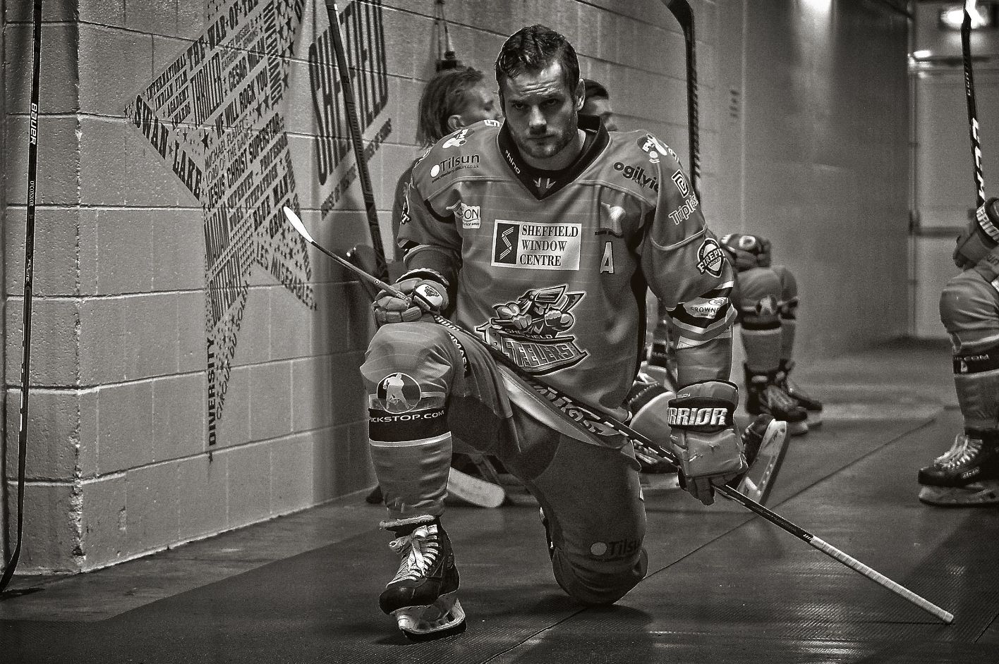Ice hockey player on one knee and looking at the camera.